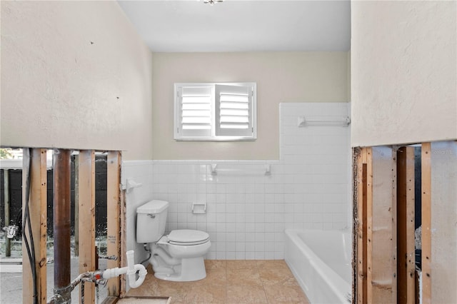 bathroom with a tub to relax in, tile walls, toilet, and tile patterned flooring