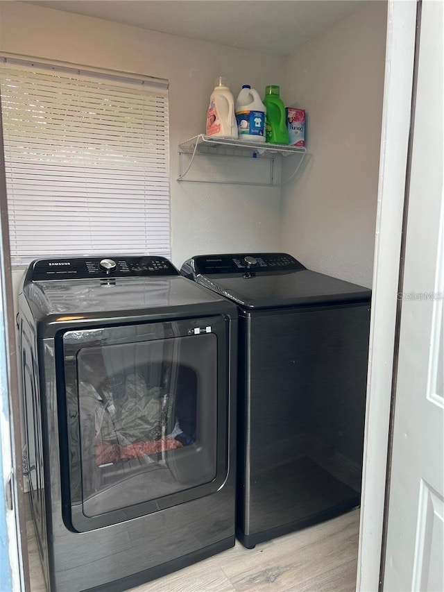 clothes washing area with washing machine and dryer and light hardwood / wood-style floors