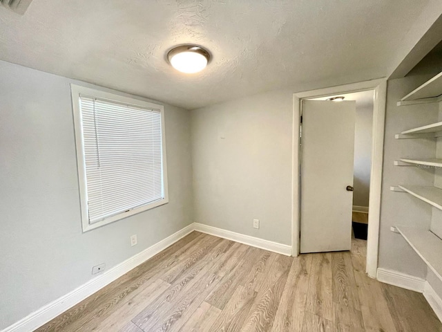 unfurnished bedroom with light hardwood / wood-style floors and a textured ceiling