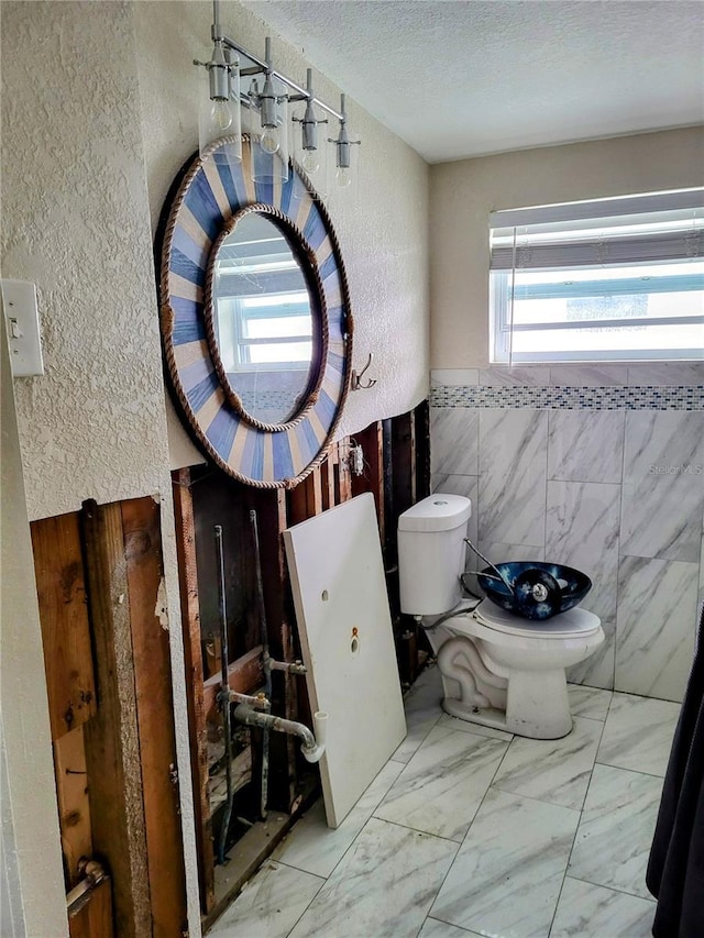 bathroom featuring tile walls, a textured ceiling, and toilet