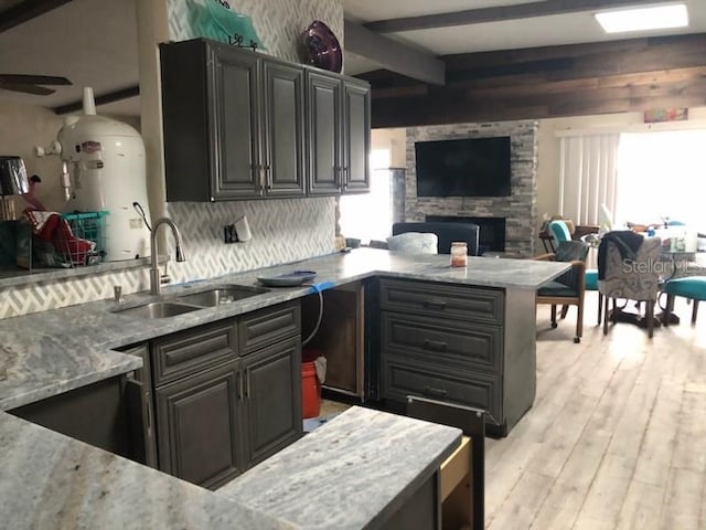 kitchen with light stone countertops, sink, light hardwood / wood-style flooring, and a wealth of natural light