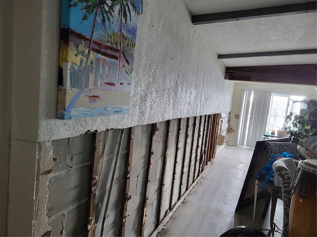 hallway with vaulted ceiling with beams and a textured ceiling