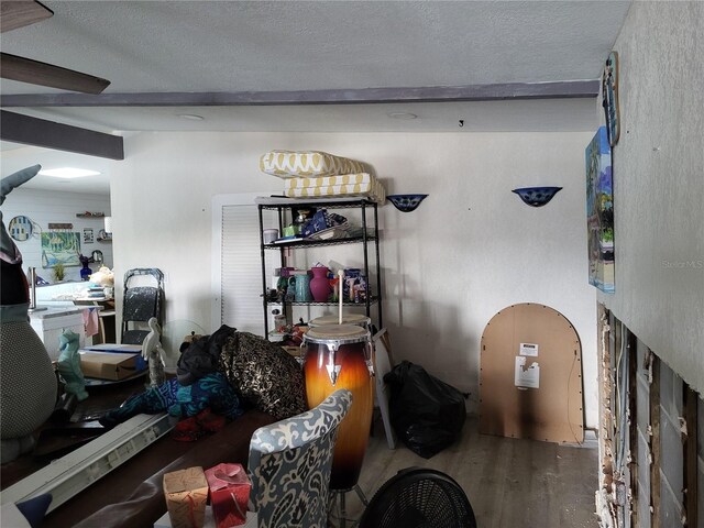 interior space with hardwood / wood-style flooring, beamed ceiling, and a textured ceiling