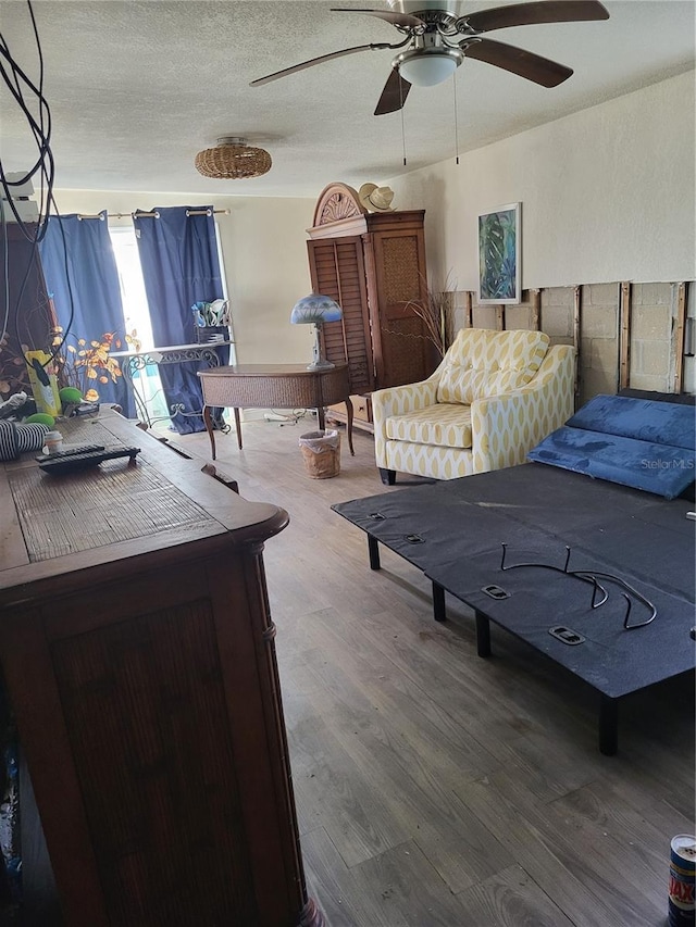 bedroom with hardwood / wood-style flooring, ceiling fan, and a textured ceiling