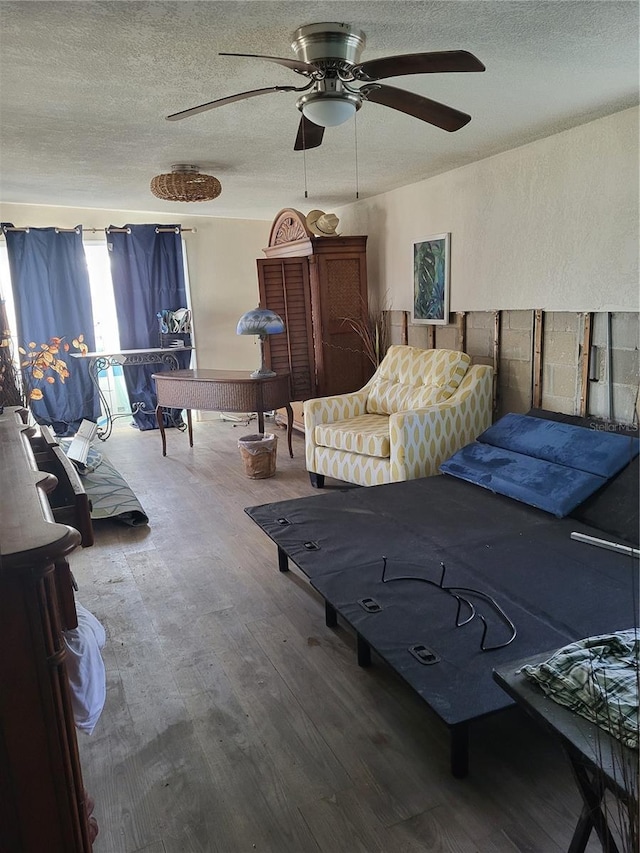 bedroom with ceiling fan, wood-type flooring, and a textured ceiling