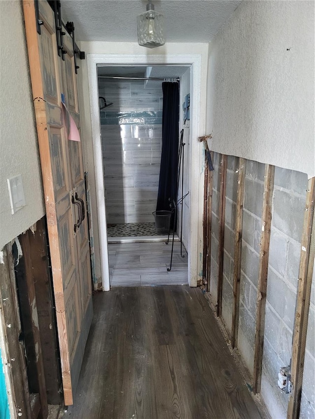 corridor with dark hardwood / wood-style flooring, a barn door, and a textured ceiling