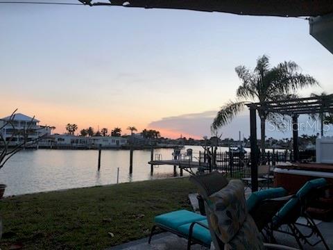 dock area with a pergola, a lawn, and a water view