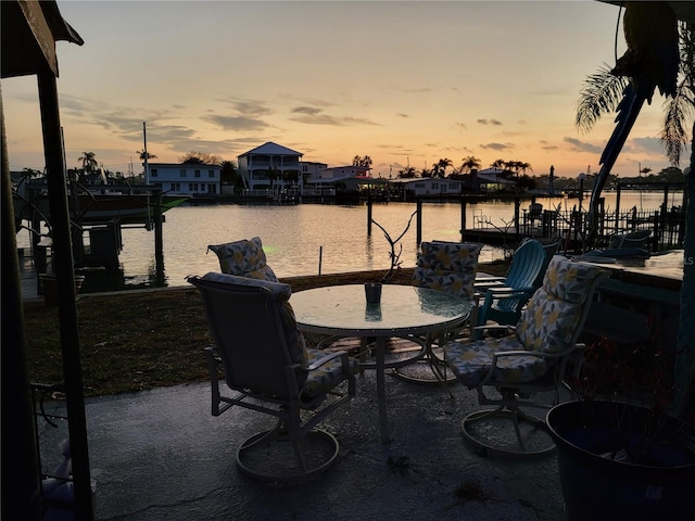 patio terrace at dusk with a water view and a dock