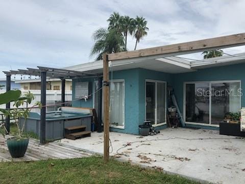 back of property featuring a hot tub, a pergola, and a patio area