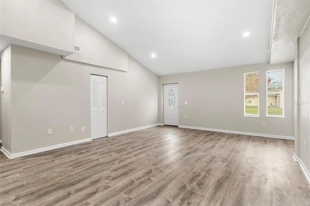 unfurnished living room with vaulted ceiling and light hardwood / wood-style flooring