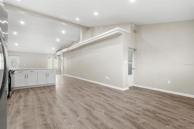 unfurnished living room with light wood-type flooring and vaulted ceiling with beams