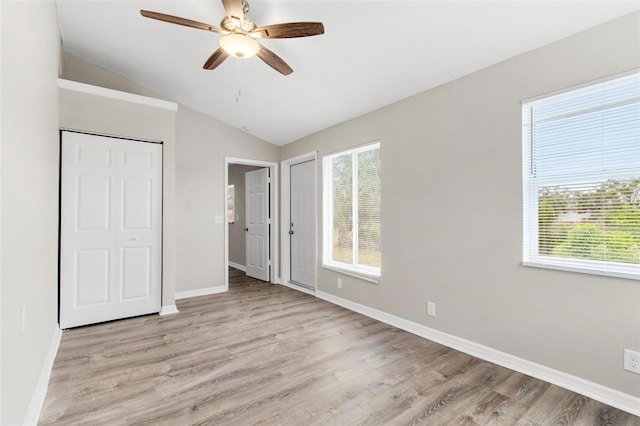 unfurnished bedroom with ceiling fan, lofted ceiling, light hardwood / wood-style flooring, and a closet