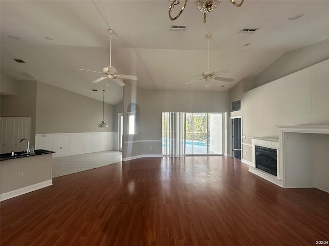 unfurnished living room with lofted ceiling, ceiling fan, sink, and hardwood / wood-style flooring