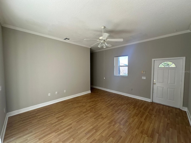 empty room with a textured ceiling, ceiling fan, ornamental molding, and hardwood / wood-style flooring