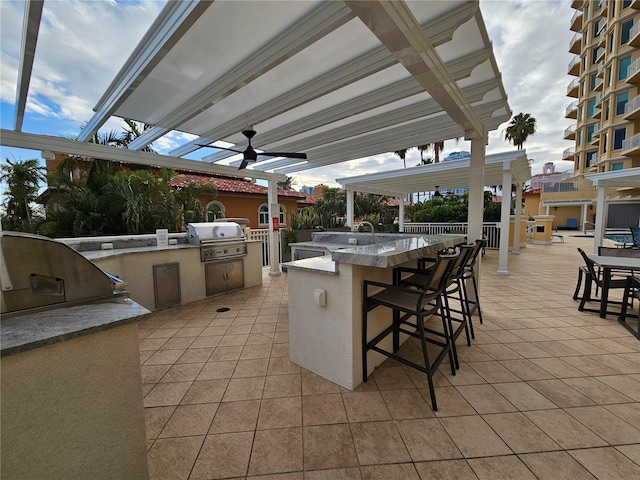 view of patio featuring a bar, exterior kitchen, grilling area, and ceiling fan