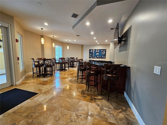 interior space with ceiling fan, a textured ceiling, and indoor bar