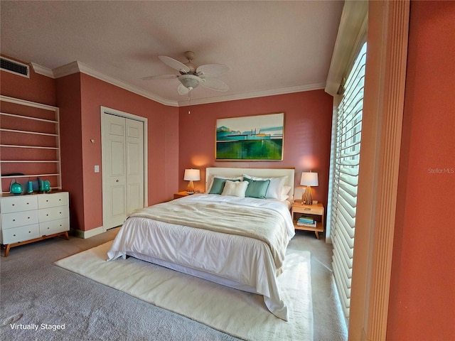 carpeted bedroom with a closet, ceiling fan, and ornamental molding