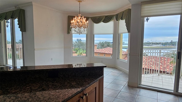 interior space featuring a notable chandelier, crown molding, hanging light fixtures, dark stone countertops, and light tile patterned flooring