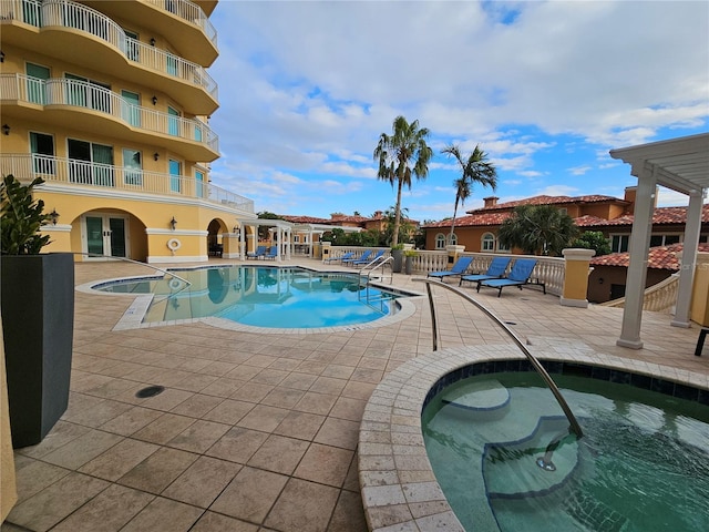 view of swimming pool featuring a patio and a hot tub