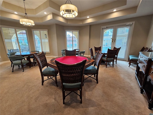 dining space with a tray ceiling and light carpet