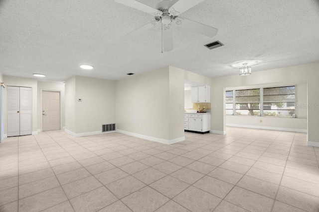 unfurnished room with ceiling fan, light tile patterned floors, and a textured ceiling