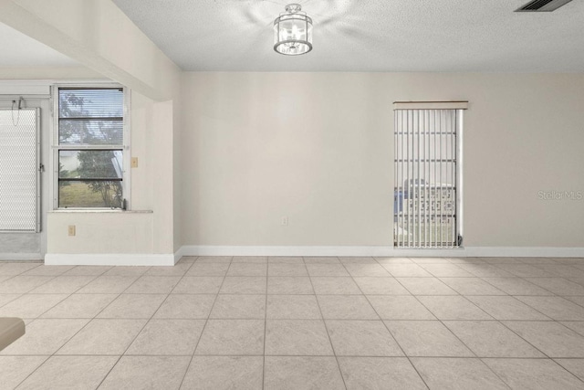 tiled empty room featuring a textured ceiling