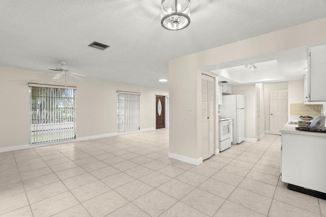 kitchen featuring light tile patterned floors, white appliances, ceiling fan, a tray ceiling, and white cabinets