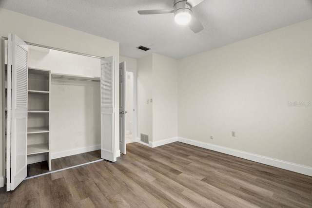 unfurnished bedroom featuring ceiling fan, hardwood / wood-style floors, a textured ceiling, and a closet