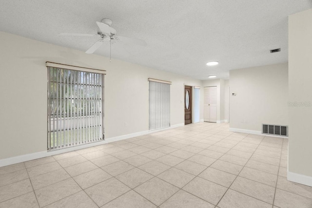 empty room with ceiling fan, light tile patterned flooring, and a textured ceiling