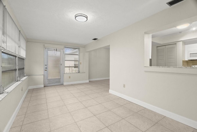 tiled empty room featuring a textured ceiling