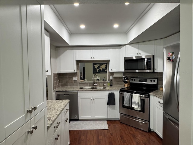 kitchen featuring backsplash, sink, white cabinetry, light stone countertops, and stainless steel appliances