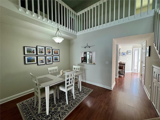 dining space with a towering ceiling and dark hardwood / wood-style floors