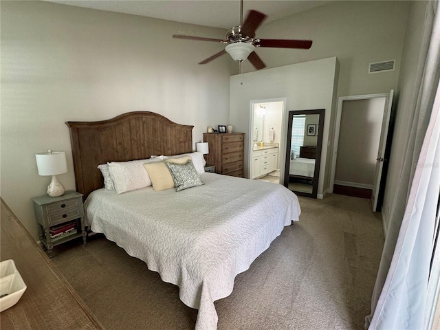 carpeted bedroom with ensuite bathroom, ceiling fan, and a high ceiling