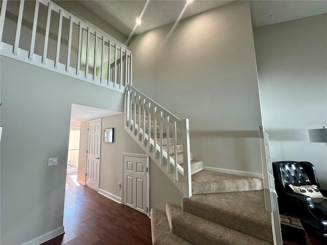 stairs featuring a towering ceiling and hardwood / wood-style flooring