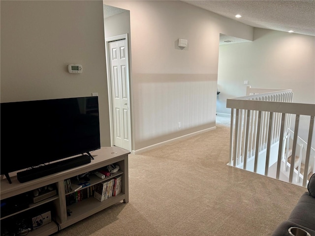 corridor featuring light carpet, vaulted ceiling, and a textured ceiling