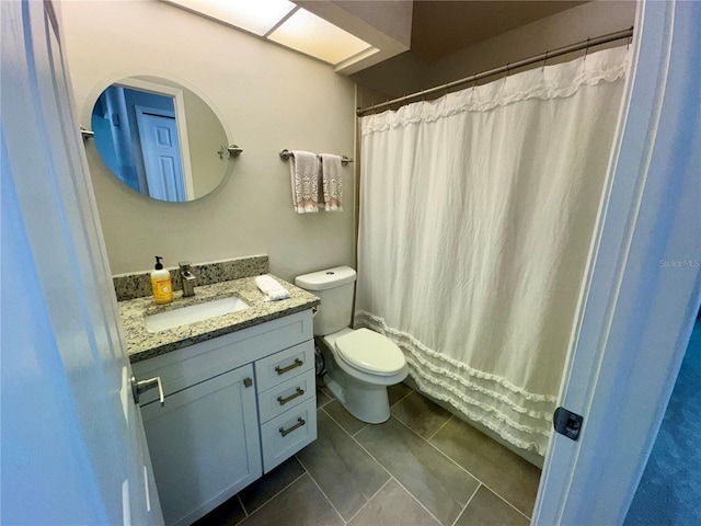 bathroom with toilet, vanity, and tile patterned flooring