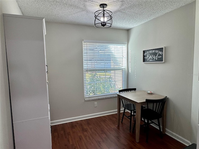 dining space with a textured ceiling, dark hardwood / wood-style flooring, and a chandelier