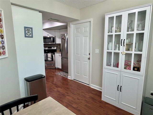 corridor featuring a textured ceiling and dark hardwood / wood-style flooring