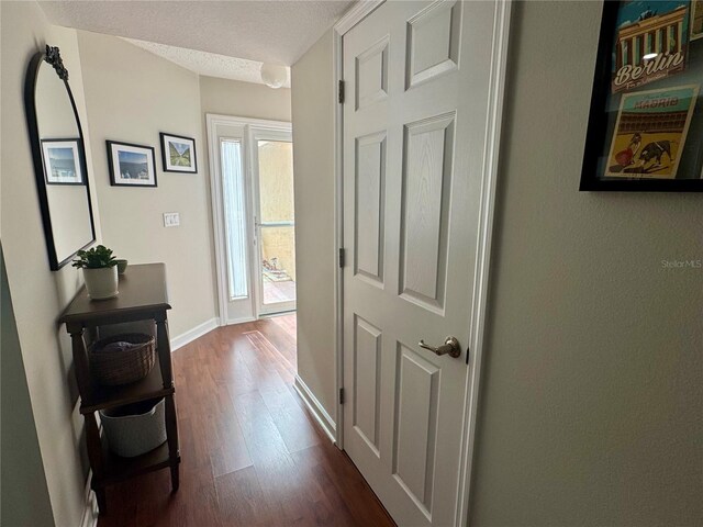 hall featuring a textured ceiling and dark wood-type flooring