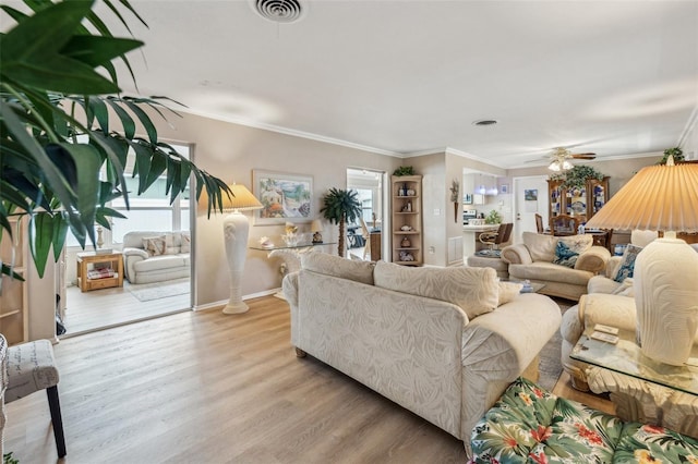 living room with light wood-type flooring, ceiling fan, and crown molding