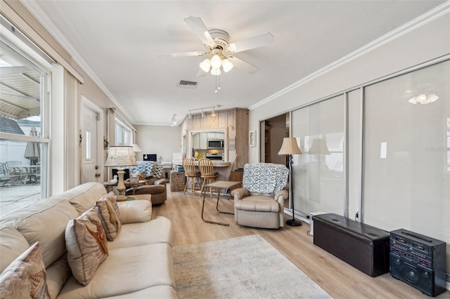 living room featuring light hardwood / wood-style floors, ceiling fan, and crown molding