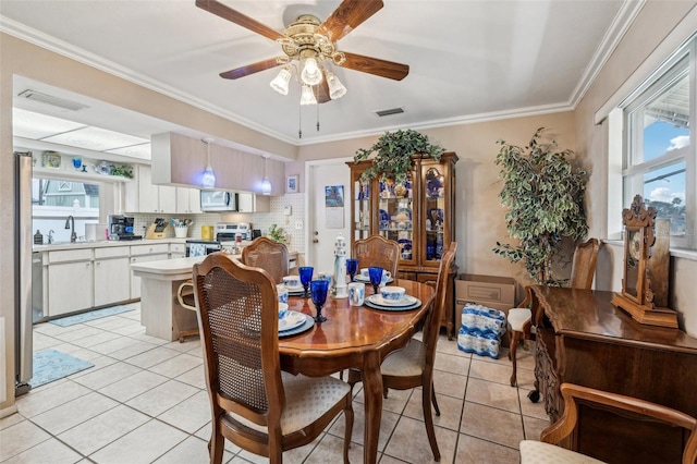 tiled dining room with ceiling fan, crown molding, and sink