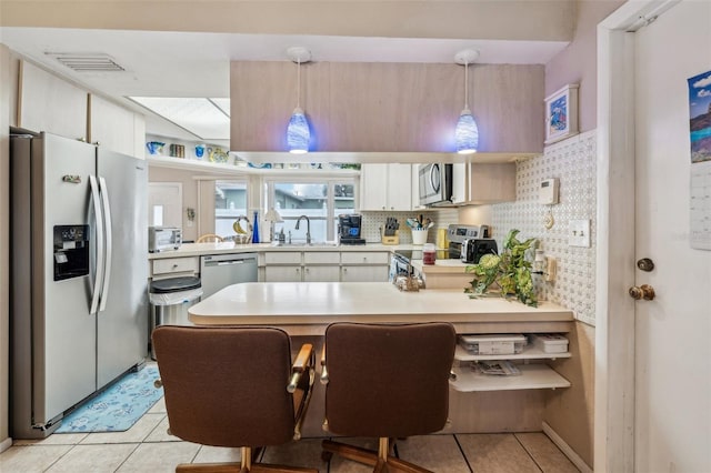 kitchen featuring stainless steel appliances, sink, light tile patterned floors, decorative backsplash, and pendant lighting