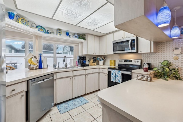 kitchen with stainless steel appliances, sink, backsplash, and hanging light fixtures