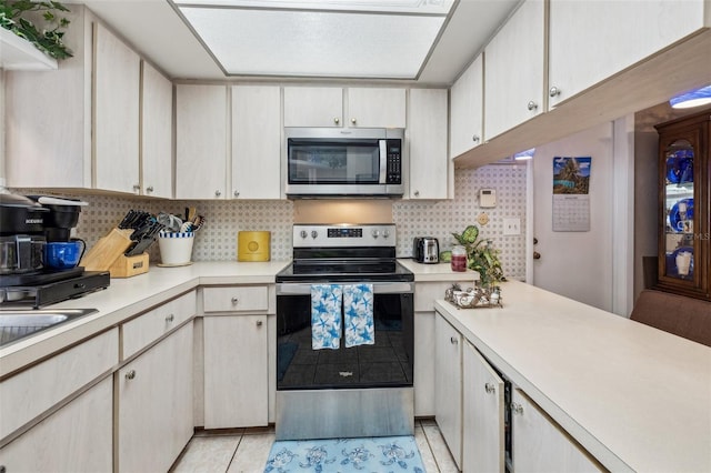 kitchen with light tile patterned floors, appliances with stainless steel finishes, and backsplash