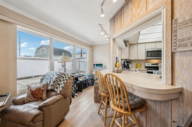 kitchen with sink, tasteful backsplash, light hardwood / wood-style flooring, crown molding, and appliances with stainless steel finishes