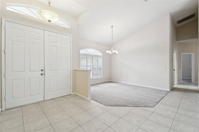 foyer with light tile patterned flooring, lofted ceiling, and a notable chandelier