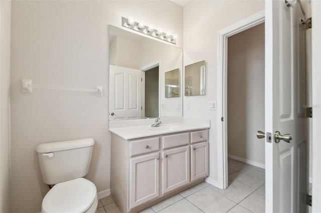 bathroom with toilet, vanity, and tile patterned floors