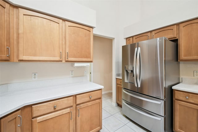 kitchen with light tile patterned floors and stainless steel fridge