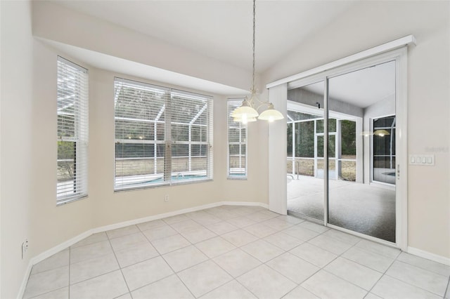 unfurnished dining area featuring tile patterned flooring, vaulted ceiling, a wealth of natural light, and an inviting chandelier